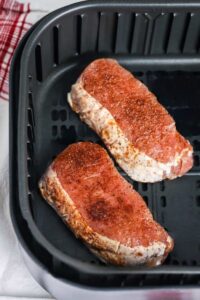 Dua potong daging babi yang dibumbui dalam penggorengan udara