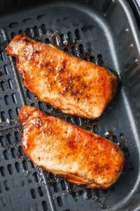 Dua potong daging babi dimasak dalam penggorengan udara