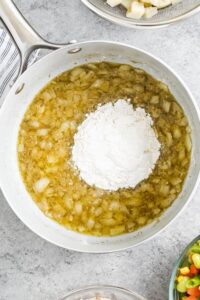 menambahkan tepung ke dalam campuran bawang bombay dan mentega untuk membuat Chicken Pot Pie Casserole