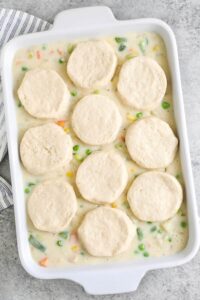menambahkan biskuit di atas bahan-bahan dalam masakan untuk membuat Chicken Pot Pie Casserole