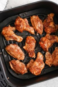 menambahkan Sayap Ayam Gosok Kering yang sudah dibumbui ke dalam penggorengan