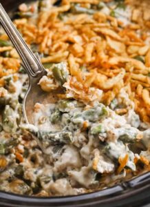 mengeluarkan sesendok Crockpot Green Bean Casserole dari panci