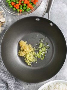 oil with garlic , ginger and green onions cooking in a pan to make Easy Fried Rice Recipe