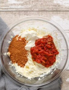 menambahkan bumbu dan salsa ke krim keju dalam mangkuk